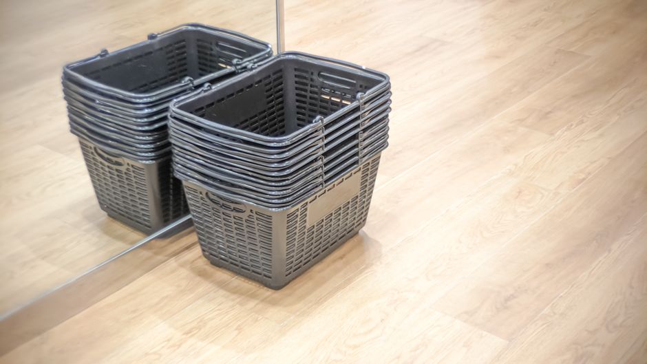 A densely packed retail storage area filled with cleaning supplies and tools, including colorful plastic buckets, various mops with different colored heads, and scrub brushes, all arranged in stacks a